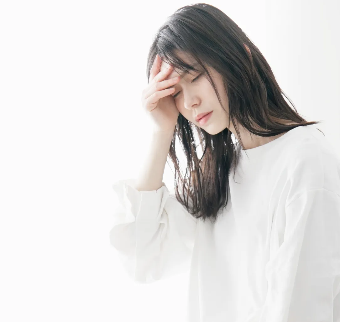 体調がすぐれず頭を抱える女性